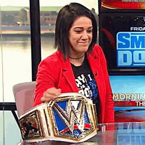 A Woman In A Red Jacket Holding A Wrestling Championship Belt GIF