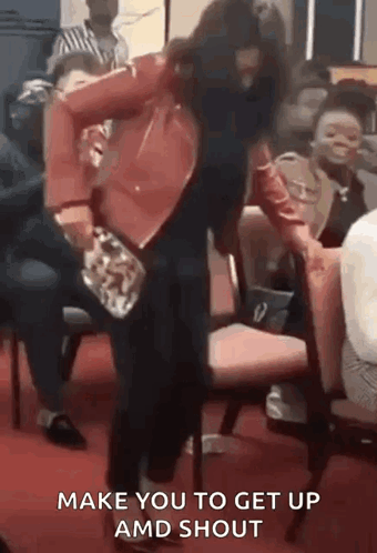 A Woman In A Red Jacket Is Dancing In Front Of A Crowd While Holding A Purse . GIF