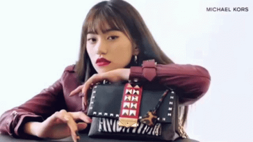 A Woman In A Red Jacket Is Holding A Michael Kors Bag . GIF
