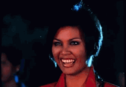 a woman in a red jacket is laughing with her mouth open .