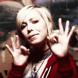 A Woman In A Red Jacket Is Making An Ok Sign With Her Hands GIF
