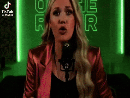 A Woman In A Red Jacket Is Singing Into A Microphone .. GIF