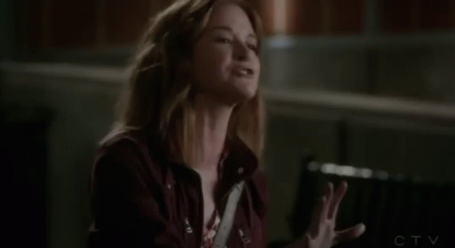 A Woman In A Red Jacket Is Sitting In A Chair And Looking At Something . GIF