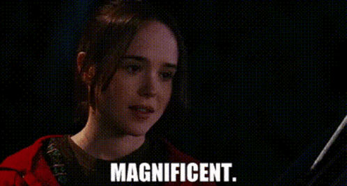 A Woman In A Red Jacket Is Smiling In A Dark Room And The Words Magnificent Are On The Screen . GIF