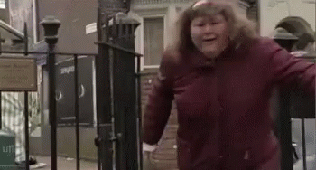 A Woman In A Red Jacket Is Standing In Front Of A Fence . GIF