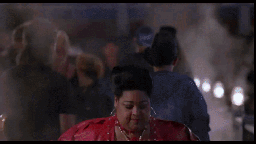 A Woman In A Red Jacket Is Standing In Front Of A Neon Sign That Says ' A ' On It GIF