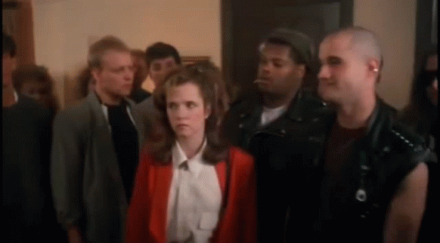 A Woman In A Red Jacket Is Surrounded By A Group Of People GIF