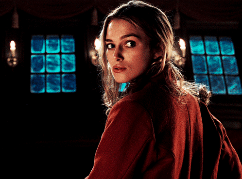 A Woman In A Red Jacket Looks Over Her Shoulder At The Camera GIF