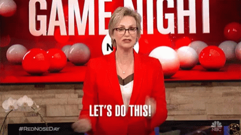 A Woman In A Red Jacket Says Let 'S Do This In Front Of A Game Night Sign GIF