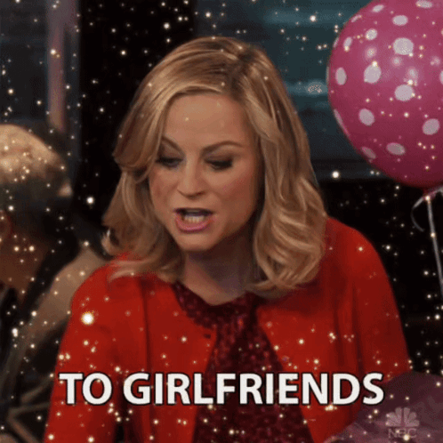 A Woman In A Red Jacket Says To Girlfriends In Front Of Pink Balloons GIF
