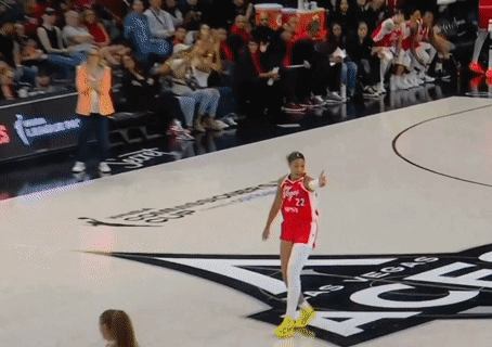 A Woman In A Red Jersey With The Number 22 On It Stands On A Basketball Court GIF