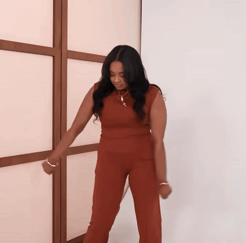 A Woman In A Red Jumpsuit Is Dancing GIF