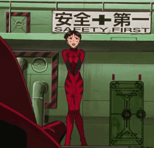 A Woman In A Red Jumpsuit Stands In Front Of A Sign That Says Safety First GIF