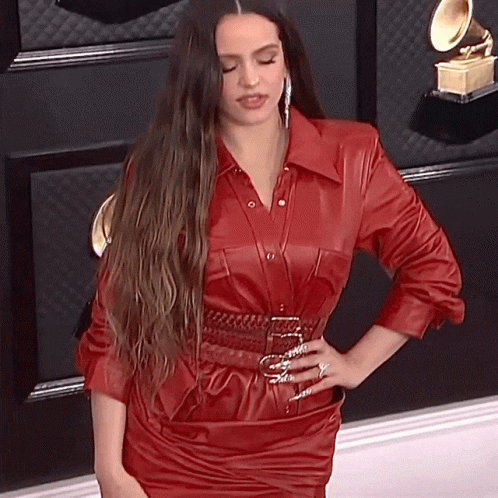 A Woman In A Red Leather Dress Stands With Her Hand On Her Hip GIF