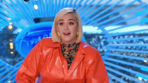 A Woman In A Red Leather Jacket Is Standing In Front Of A Blue Background And Smiling . GIF