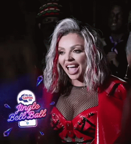 A Woman In A Red Outfit Is Smiling In Front Of A Jingle Bell Ball Sign GIF