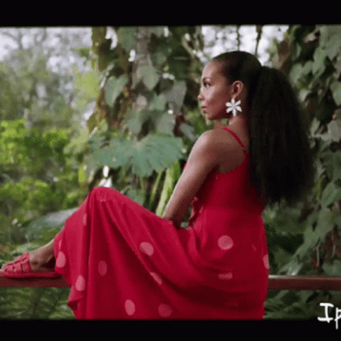 A Woman In A Red Polka Dot Dress Is Sitting On A Railing GIF