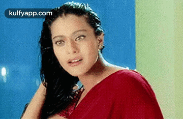 A Woman In A Red Saree Is Looking At The Camera While Holding Her Hair . GIF