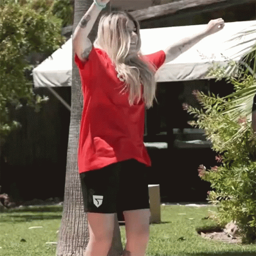 A Woman In A Red Shirt And Black Shorts With The Letter J On The Shorts GIF