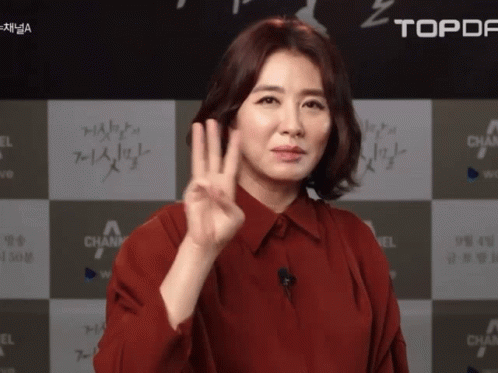 A Woman In A Red Shirt Giving A Peace Sign GIF