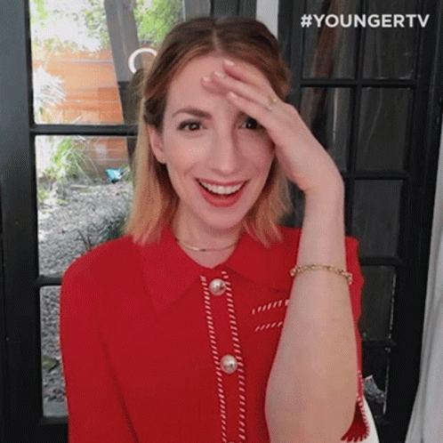 A Woman In A Red Shirt Is Covering Her Face With Her Hand And Smiling . GIF