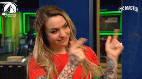 A Woman In A Red Shirt Is Giving A Thumbs Up In Front Of A Paramount Network Sign GIF