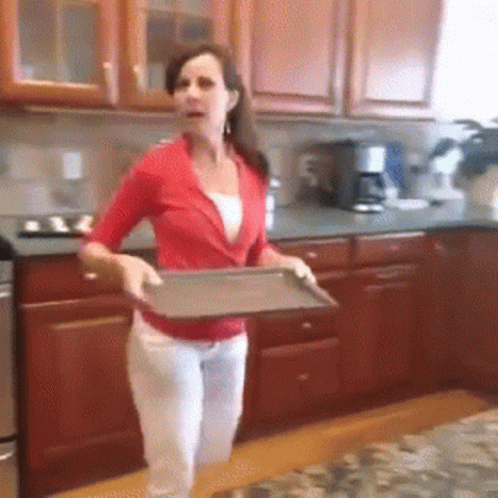 A Woman In A Red Shirt Is Holding A Metal Tray In A Kitchen GIF