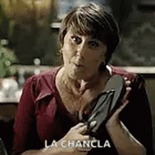 A Woman In A Red Shirt Is Holding A Pair Of Flip Flops . GIF