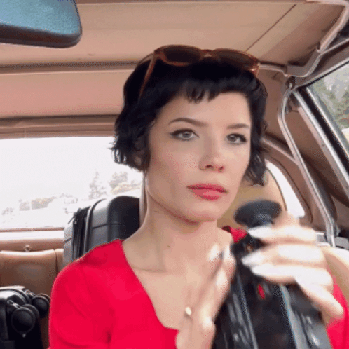 A Woman In A Red Shirt Is Sitting In A Car GIF