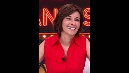 a woman in a red shirt is smiling and looking at the camera .