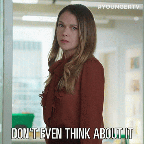 A Woman In A Red Shirt Is Standing In Front Of A Sign That Says " Do N't Even Think About It " GIF