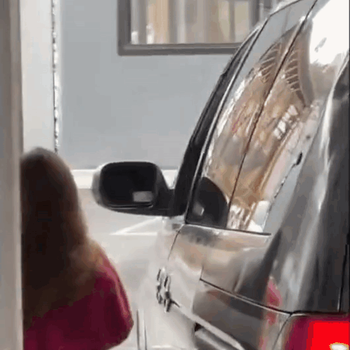A Woman In A Red Shirt Is Standing Next To A Black Suv . GIF