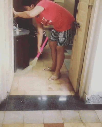 A Woman In A Red Shirt Is Sweeping The Floor With A Broom GIF