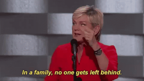 A Woman In A Red Shirt Is Talking Into A Microphone And Says In A Family No One Gets Left Behind GIF