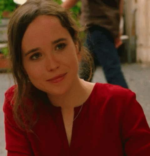 A Woman In A Red Shirt Looks At The Camera GIF