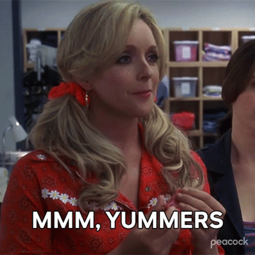 A Woman In A Red Shirt Says " Mmmm Yummers " While Holding Something In Her Hand GIF