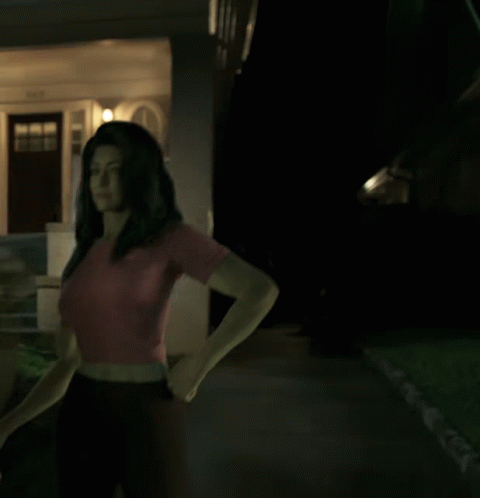 A Woman In A Red Shirt Stands In Front Of A House GIF
