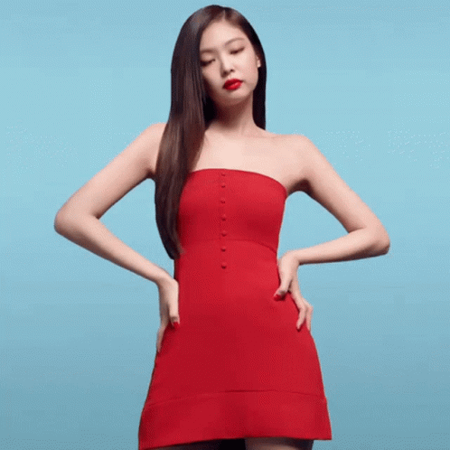 A Woman In A Red Strapless Dress Stands With Her Hands On Her Hips Against A Blue Background GIF