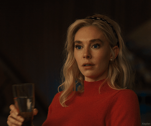 A Woman In A Red Sweater Holds A Glass Of Water In Her Right Hand GIF