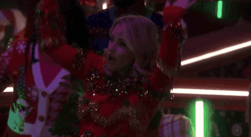 A Woman In A Red Sweater Is Dancing In A Club With Other People . GIF