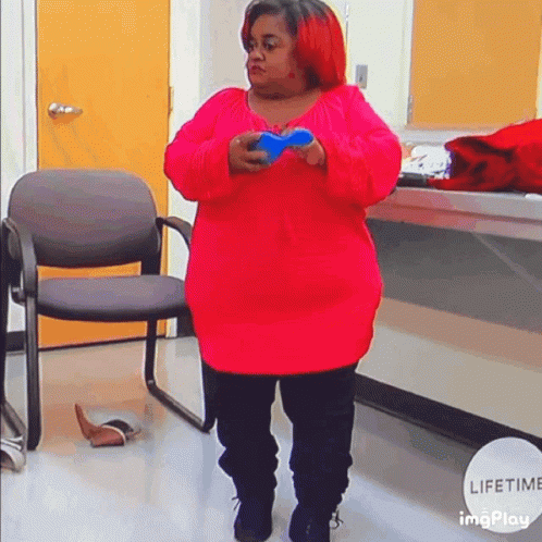 A Woman In A Red Sweater Is Holding A Blue Object In Her Hands GIF
