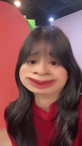 A Woman In A Red Sweater Is Making A Funny Face With Her Mouth Wide Open . GIF