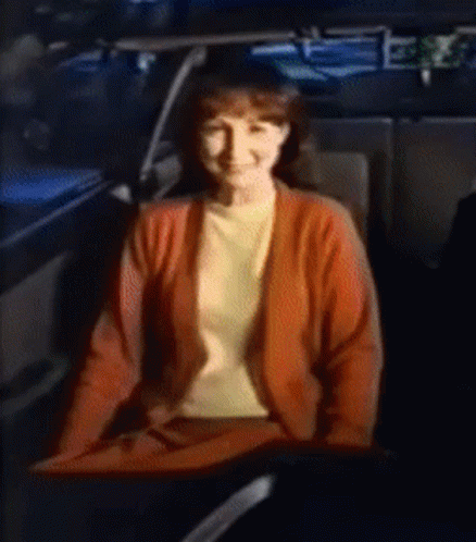 A Woman In A Red Sweater Is Sitting In The Back Seat Of A Car GIF