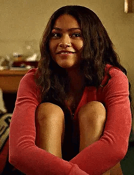 A Woman In A Red Sweater Is Sitting On The Floor With Her Legs Crossed . GIF