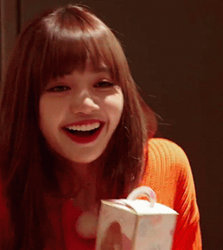 A Woman In A Red Sweater Is Smiling While Holding A Box GIF