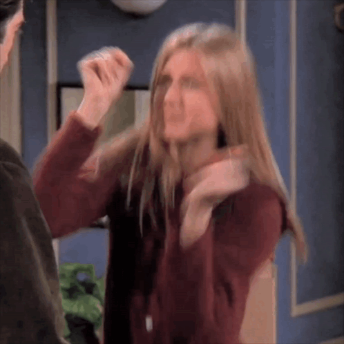 A Woman In A Red Sweater Is Standing Next To A Man And Making A Funny Face . GIF