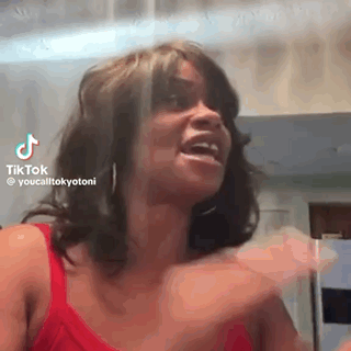 A Woman In A Red Tank Top Is Making A Funny Face And Laughing . GIF
