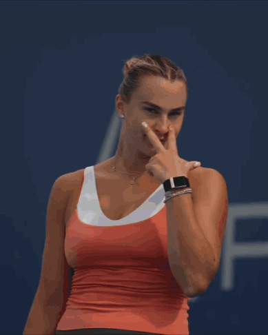 a woman in a red tank top is pointing at something