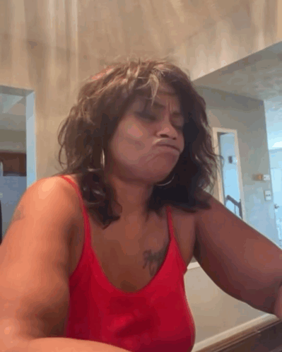 a woman in a red tank top with a tattoo on her chest