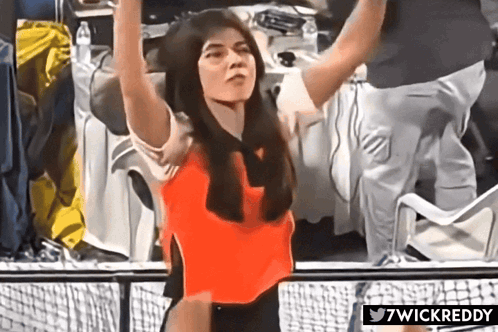 A Woman In A Red Top Is Standing In Front Of A Fence With 7Wickreddy Written Below Her GIF